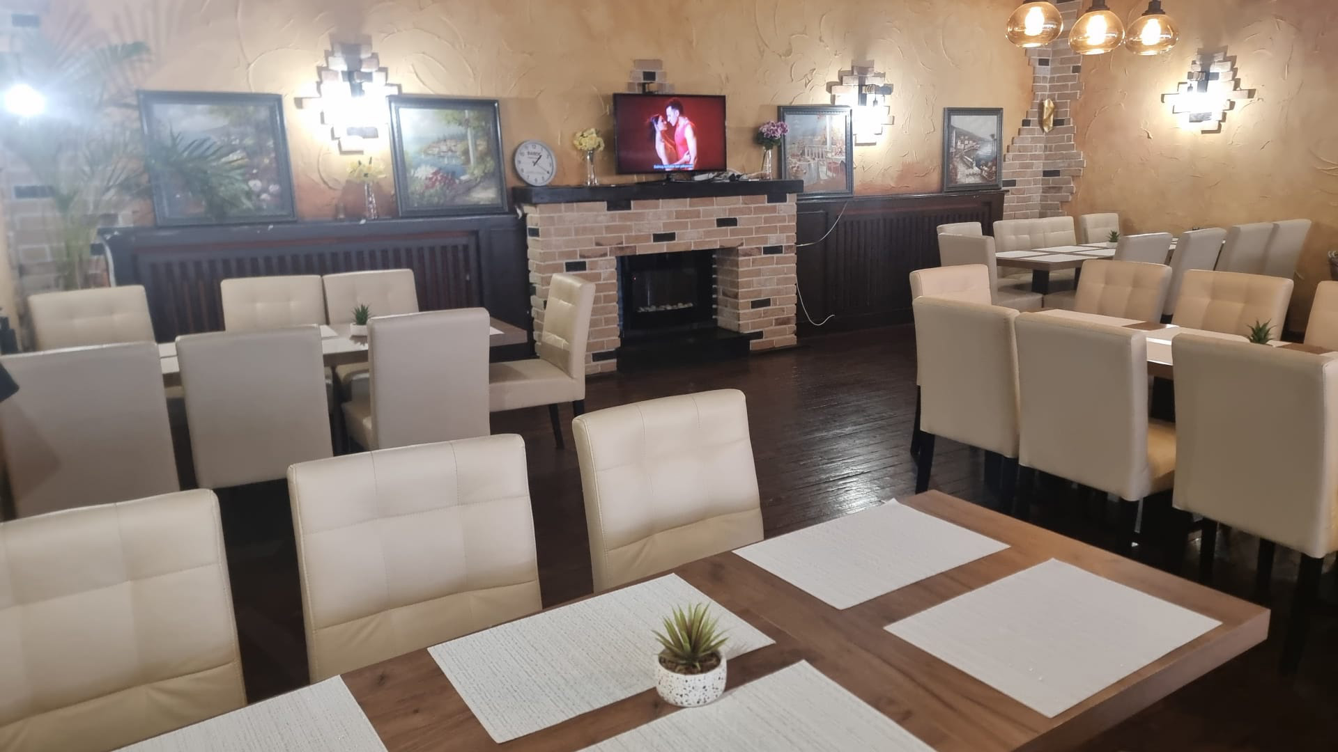 Ein leerer Speisesaal mit beigen Stühlen, gemusterten Wänden und einem Bild an der Ziegelwand.