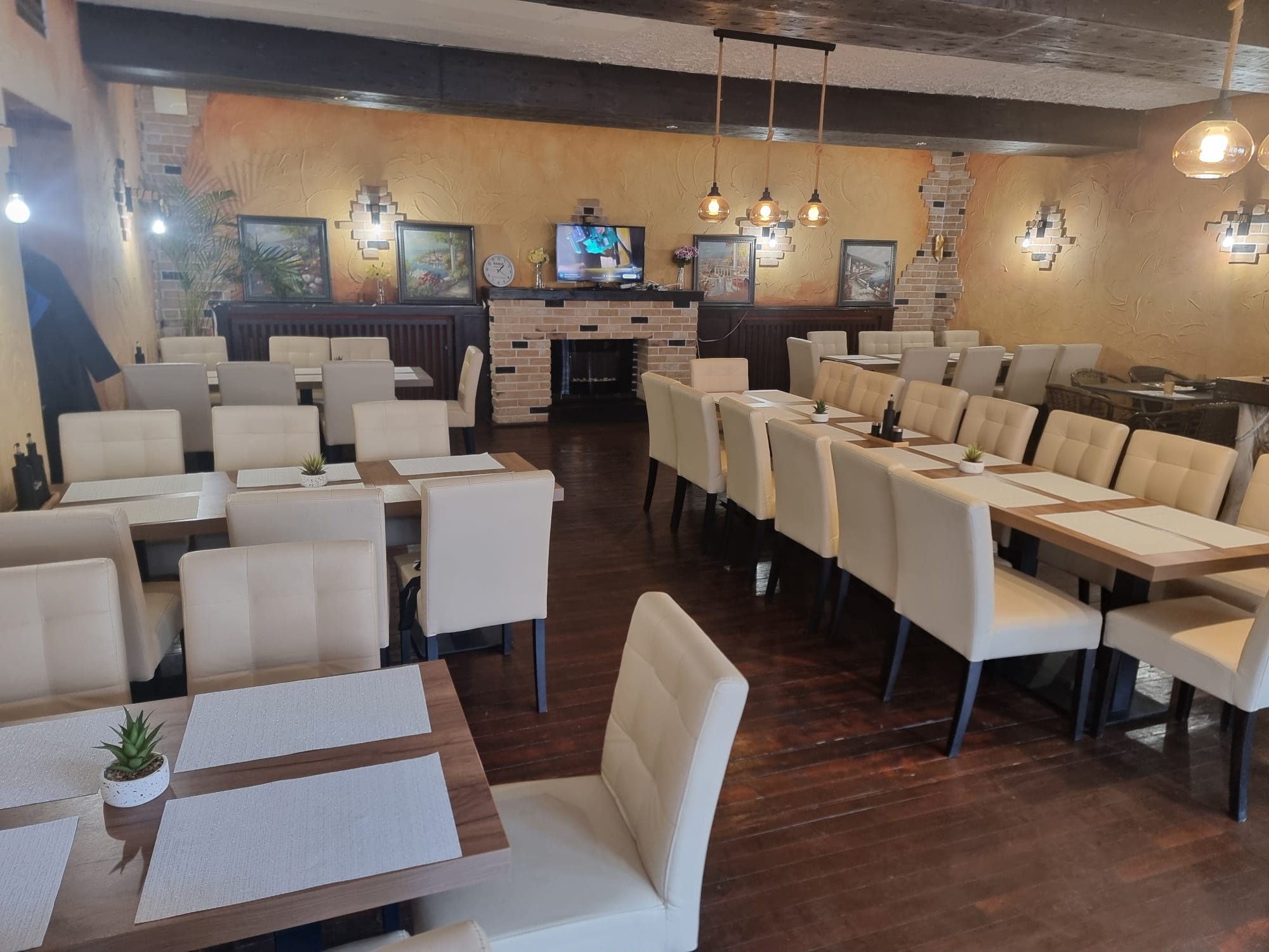 Ein leerer Speiseraum mit beigen Stühlen und Holztischen, gemütlich beleuchtet.